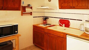 Een kleine keuken met een magnetron, spoelbak en koffiezetapparaat.