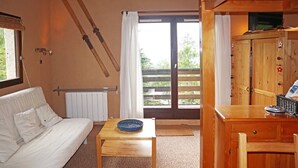 Habitació acollidora amb un sofà blanc, una taula de fusta i vista cap a l'exterior a través d'una àmplia porta corredissa.