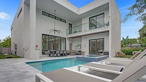 Uma casa moderna com dois andares, piscina, área de estar externa e uma varanda.