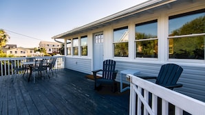 A wooden deck with a table and chairs, a small table with a chair, and a white railing. - Making Memories-Pet Friendly Cottage w/ Sun Deck;Easy Beach Access; WiFi/TV (Edisto Beach)