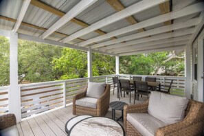 A covered outdoor seating area with wicker furniture and a table, surrounded by a white railing and trees. - Making Memories-Pet Friendly Cottage w/ Sun Deck;Easy Beach Access; WiFi/TV (Edisto Beach)
