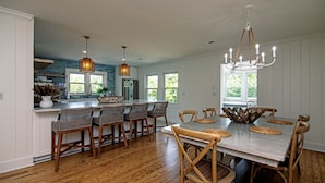 A spacious kitchen with a large island, wooden chairs, and a chandelier. - Making Memories-Pet Friendly Cottage w/ Sun Deck;Easy Beach Access; WiFi/TV (Edisto Beach)