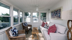 A sunroom with wicker furniture, a white sofa, and a view of the outside. - Making Memories-Pet Friendly Cottage w/ Sun Deck;Easy Beach Access; WiFi/TV (Edisto Beach)