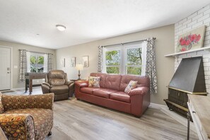 Un salon avec un canapé en cuir marron, un fauteuil à motifs et une cheminée.