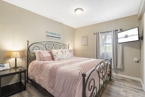 Une chambre à coucher avec un lit, une table de chevet, une lampe et un téléviseur fixé au mur.