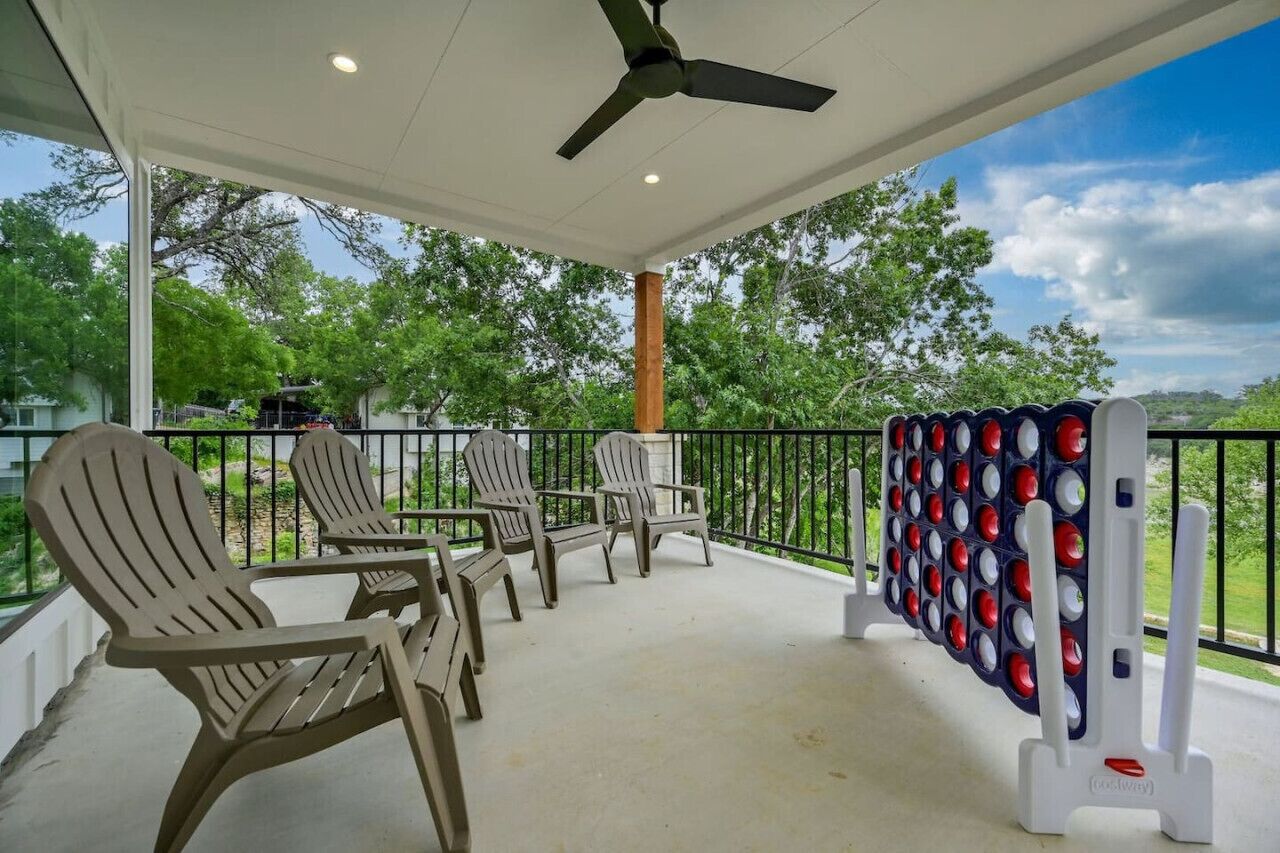 Área externa coberta com cadeiras Adirondack, ventilador de teto e mesa de bilhar.