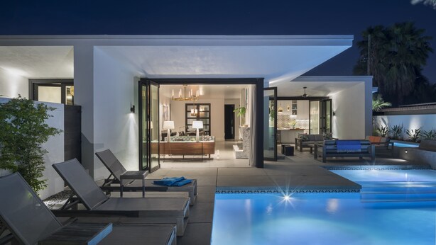 Ein modernes Haus mit Swimmingpool, Liegestühlen und einem hellen Innenraum.