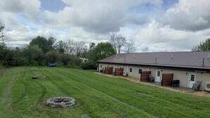 A large, open grassy area with a stable and a fenced paddock. - End-unit apartment with spacious lawn (Burdett)