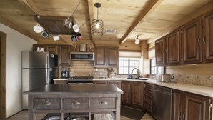 A spacious kitchen with wooden cabinets, stainless steel appliances, and a central island with storage drawers and a sink. - Private Sauna and Stunning Views of Mesa Verde, Walk to Mancos State Park (Mancos)