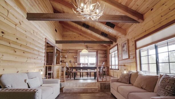 A log cabin interior with a wooden ceiling, a dining area, and a sofa. - Private Sauna and Stunning Views of Mesa Verde, Walk to Mancos State Park (Mancos)