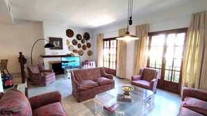 A living room with a fireplace, multiple armchairs, a coffee table, and a television. - House on the beachfront. (Estepona)