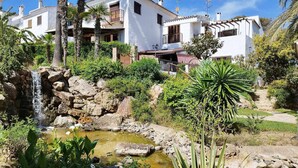 A residential area with white houses, a small waterfall, and lush greenery. - House on the beachfront. (Estepona)