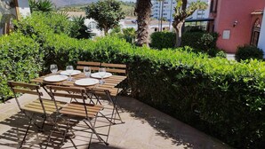 An outdoor dining area with a table set for four, surrounded by lush greenery and a view of a mountain range. - House on the beachfront. (Estepona)