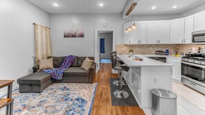 A modern kitchen with white cabinets, a central island, and stainless steel appliances. - Modern 2BHK - 15 mins bus ride to Time Square, NYC (West New York)