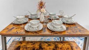 A dining table set with plates, bowls, and cutlery, centered with a vase of dried flowers. - Modern 2BHK - 15 mins bus ride to Time Square, NYC (West New York)