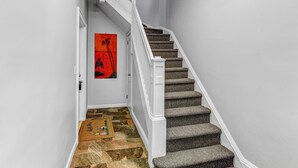 A staircase with carpeted steps and white railings, leading to a door with a red artwork on the wall. - Modern 2BHK - 15 mins bus ride to Time Square, NYC (West New York)
