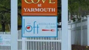 A sign for 'The Cove at Yarmouth' with a logo of a bird and mentions a restaurant/bar. - Luxury Resort with Restaurants , 5 minutes to the beach (West Yarmouth)