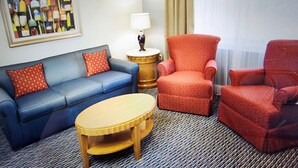 A hotel room with a blue sofa, a red armchair, a wooden coffee table, and a lamp on a side table. - Luxury Resort with Restaurants , 5 minutes to the beach (West Yarmouth)