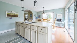 A kitchen with a large island, wooden cabinets, and a dining area with a table and chairs.