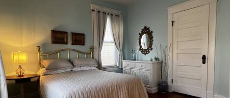 A bedroom with a bed, nightstands, a dresser, a mirror, and a door.