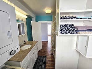 Une salle de bain compacte pour camping-car, comprenant un lavabo, un miroir et des placards de rangement.