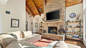 Una sala de estar acogedora con chimenea de piedra, un televisor de pantalla plana grande y un sofá cómodo.