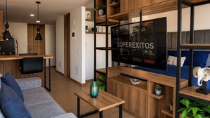 A modern living room with a sofa, a coffee table, a TV, and built-in wooden shelving.