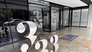 A modern building entrance with a large metallic number '333' sculpture, glass doors, and a tiled floor.