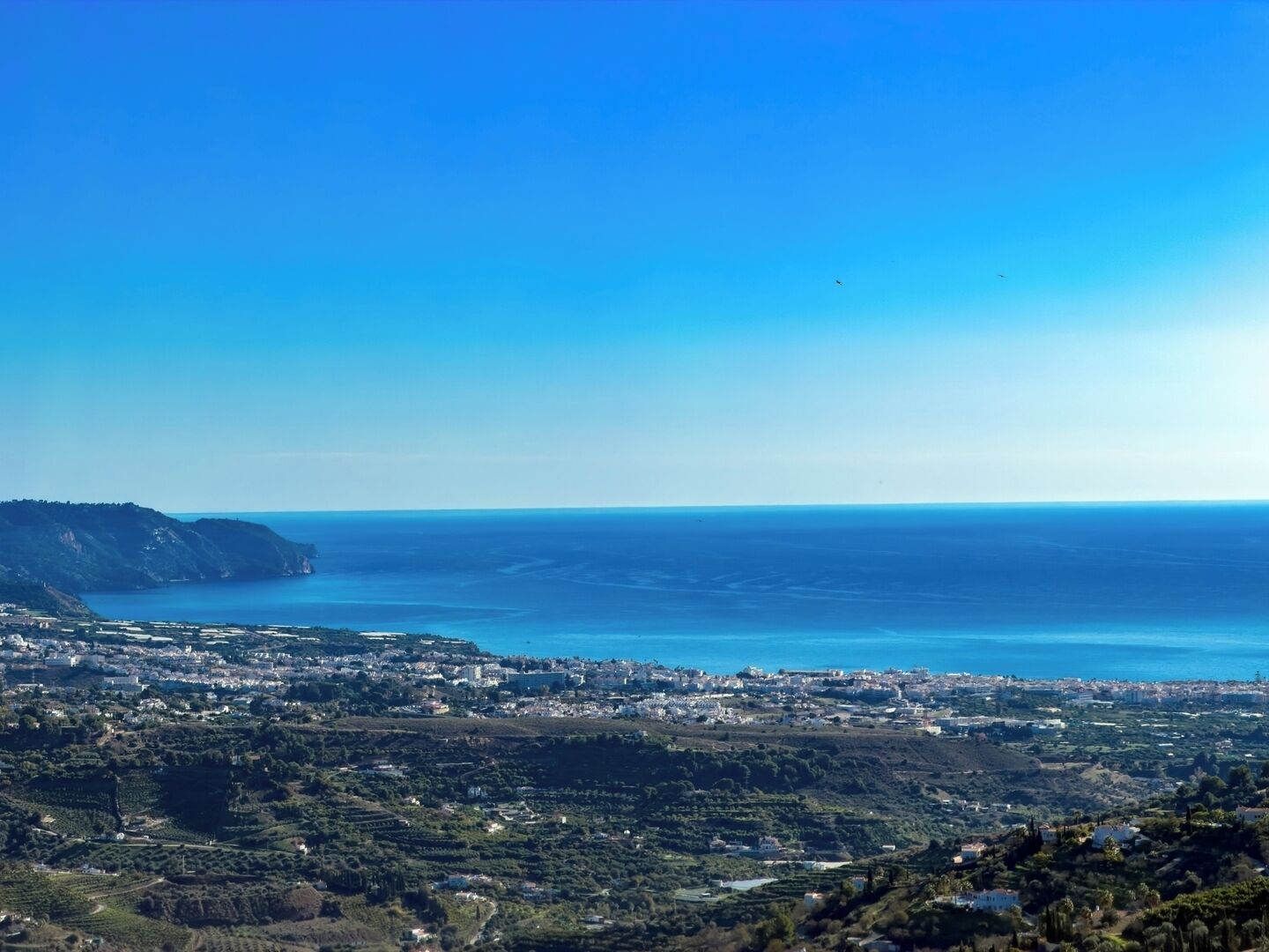 A coastal cityscape with a view of the sea and hills.