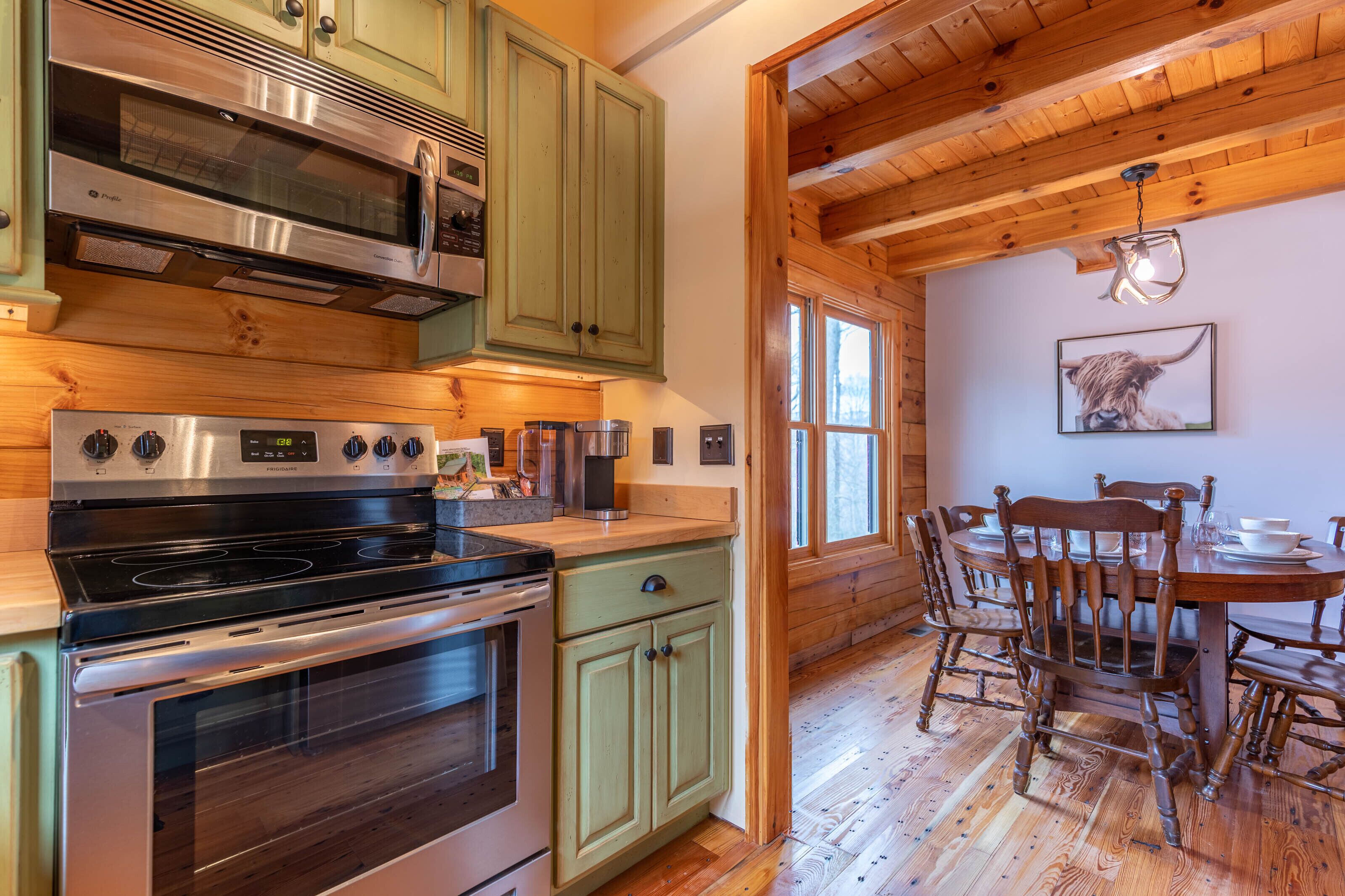 A kitchen with stainless steel appliances, wooden cabinets, and a dining area with a wooden table and chairs.