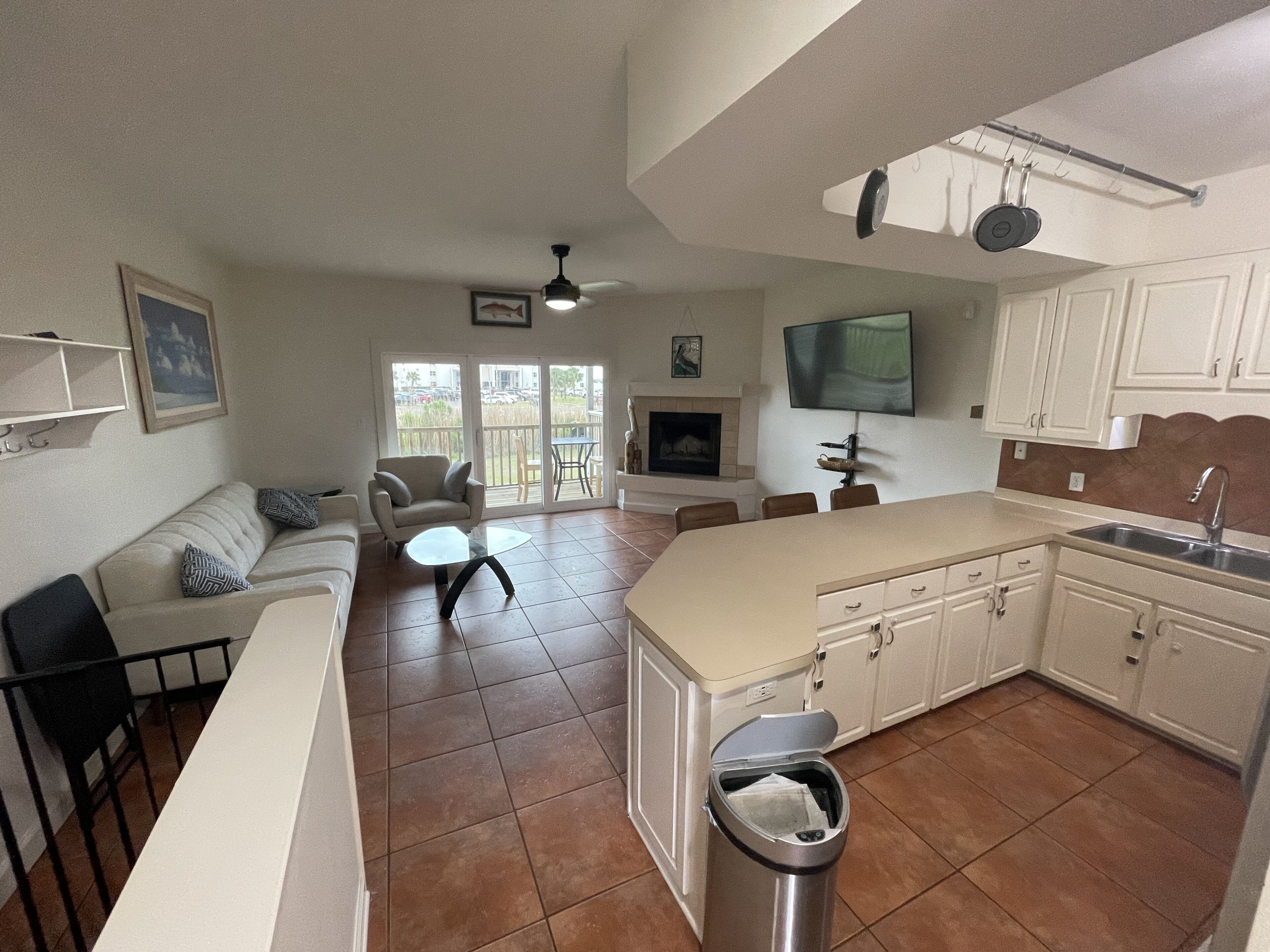 A spacious living area with a sofa, coffee table, and a fireplace. A kitchen with white cabinets and a large island is visible.