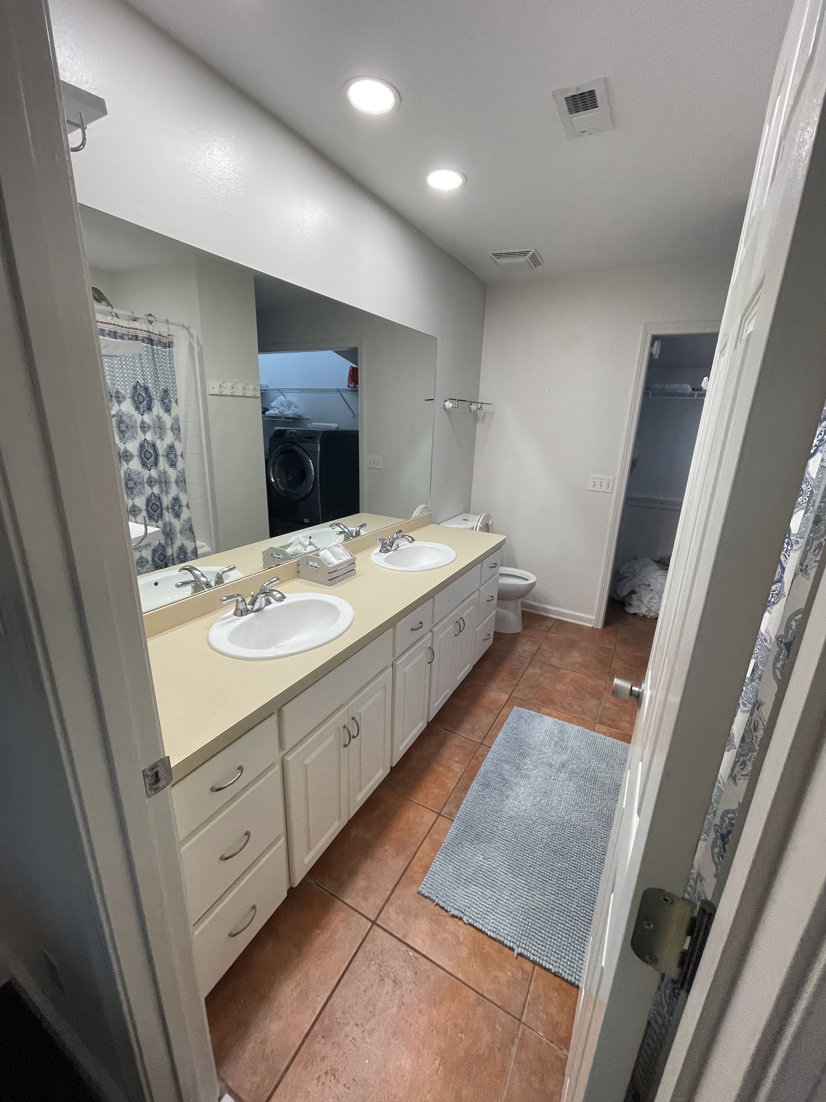 Un baño moderno con tocador doble, espejo, inodoro y zona de ducha.