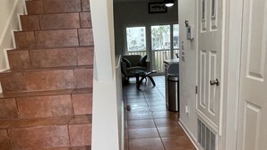 Un escalier recouvert de carreaux bruns mène à une pièce d’où l’on a vue sur la rue.