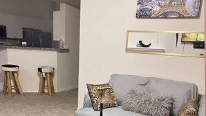 Een woonkamer met een glazen salontafel, een grijze bank en een klein model van de Eiffeltoren.