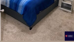 Een slaapkamer met een groot bed, een nachtkastje, een spiegel en een schilderij aan de muur.