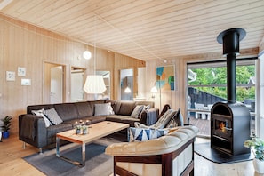 Una sala de estar acogedora con un sofá modular, una mesa de centro, una chimenea y un ventanal grande.