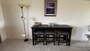 A dining area with a table and chairs, a floor lamp, and a framed picture on the wall. - Beautiful Ocean view of Sunny South Shore at Poipu Beach in Kauai (Koloa)