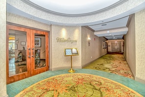 A hotel hallway with a curved carpet, a Christmas tree, and a sign that reads 'Water Scapes.'