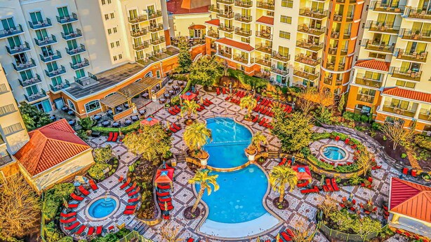 Un hotel amb diverses plantes, piscines exteriors i un pati paisatjat amb zones d'estar.