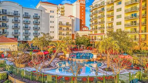 Un hotel amb diverses plantes, piscina exterior i vegetació als voltants.