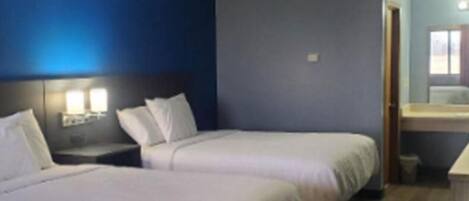 Een hotelkamer met twee bedden, een nachtkastje en een zichtbare badkamer door een open deur.