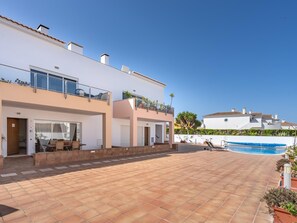 Una casa moderna de dos pisos con piscina, mobiliario exterior y cielo despejado.