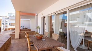 A patio with a wooden table and chairs, a potted plant, and a sliding glass door leading to an outdoor area. - Cozy Retreat for Couples in Burgau (Burgau)