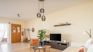 A living room with a sofa, a TV, a coffee table, a plant, and a swing chair. - Cozy Retreat for Couples in Burgau (Burgau)