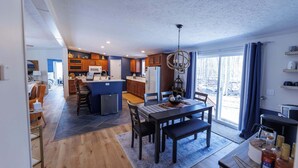 A modern kitchen with a dining area, wooden cabinets, and a chandelier. - Private, Updated Baileys Harbor Home: The Roost (Baileys Harbor)