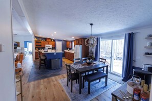 A modern kitchen with a dining area, wooden cabinets, and a chandelier. - Private, Updated Baileys Harbor Home: The Roost (Baileys Harbor)