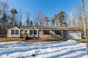 A single-story house with a front porch, a garage, and a yard covered in snow. - Private, Updated Baileys Harbor Home: The Roost (Baileys Harbor)