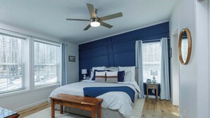 A bedroom with a bed, a ceiling fan, a bedside table, a nightstand, and a window with blinds. - Private, Updated Baileys Harbor Home: The Roost (Baileys Harbor)