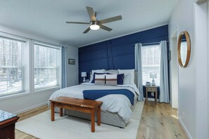 A bedroom with a bed, a ceiling fan, a bedside table, a nightstand, and a window with blinds. - Private, Updated Baileys Harbor Home: The Roost (Baileys Harbor)