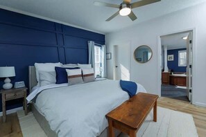 Une chambre Ă coucher avec un lit, une table de chevet, une commode et un ventilateur de plafond.